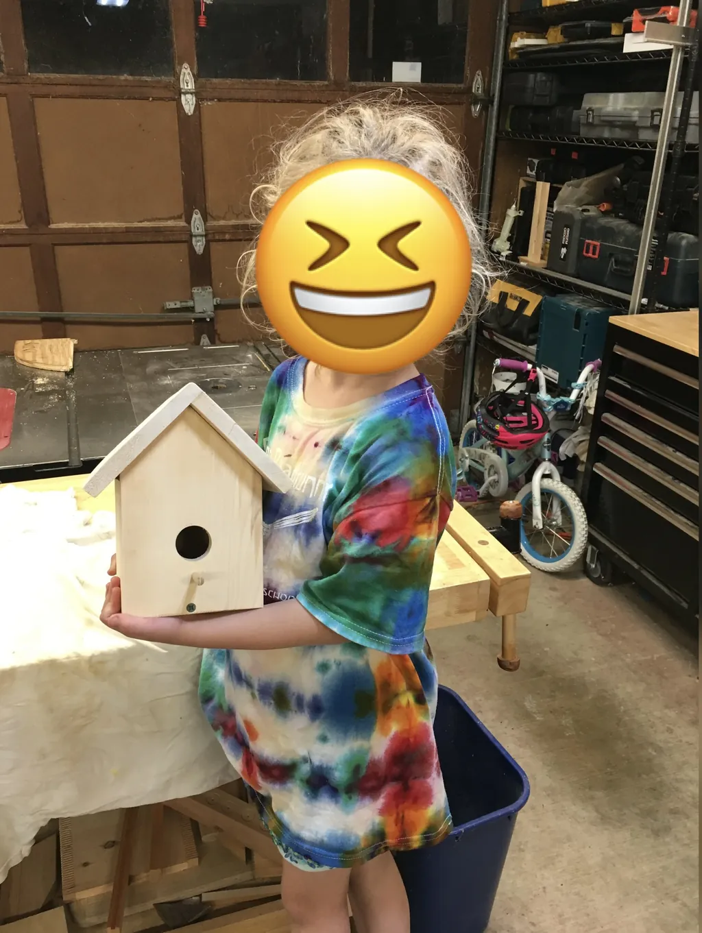 A young builder holding the birdhouse they made at a Tinkery workshop